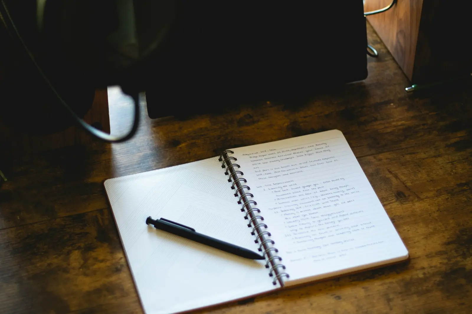 Open notebook and pen on a wooden desk